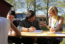 drei Jugendliche sitzen am Tisch über ihren Schulbüchern zusammen