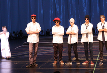 Fünf Jungs stehen mit verschränkten Armen auf einer Bühne