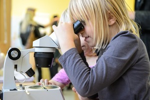 Ein Mädchen schaut durch ein Mikroskop.