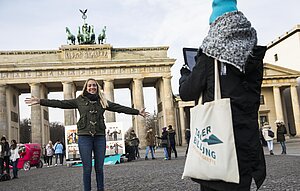 Ein Mädchen mit ausgetsreckten Armen vor dem Brandenburger Tor