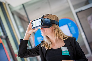Eine blonde Frau schaut durch eine Virtual Reality Brille