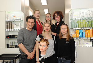Oliver Mommsen und das Team des Salons Haarphilosophie posieren in einem Gruppenbild.