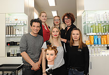 Oliver Mommsen und das Team des Salons Haarphilosophie posieren in einem Gruppenbild.