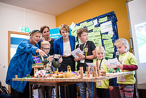 Heike Kahl, Geschäftsführerin DKJS, Annett Hofmann, Frau an der Seite des sächsischen Ministerpräsidenten Kretschmer, und Elke Büdenbender, DKJS-Schirmherrin, schauen sich Modell zur Schulhofneugestaltung an