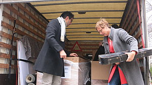 Eine Frau und ein Mann laden Instrumente von einem Lastwagen ab.