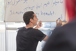 Ein Junge schreibt an ein Whiteboard.