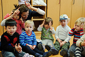 Kita-Erzieherin spielt mit Gruppe von Kindern.