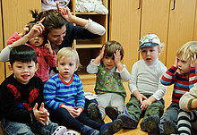 Kita-Erzieherin spielt mit Gruppe von Kindern.