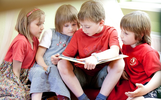 Ein Junge liest seinen Freunden aus einem Buch vor. Bildquelle: DKJS